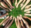 hands coming together in a circle over the grass